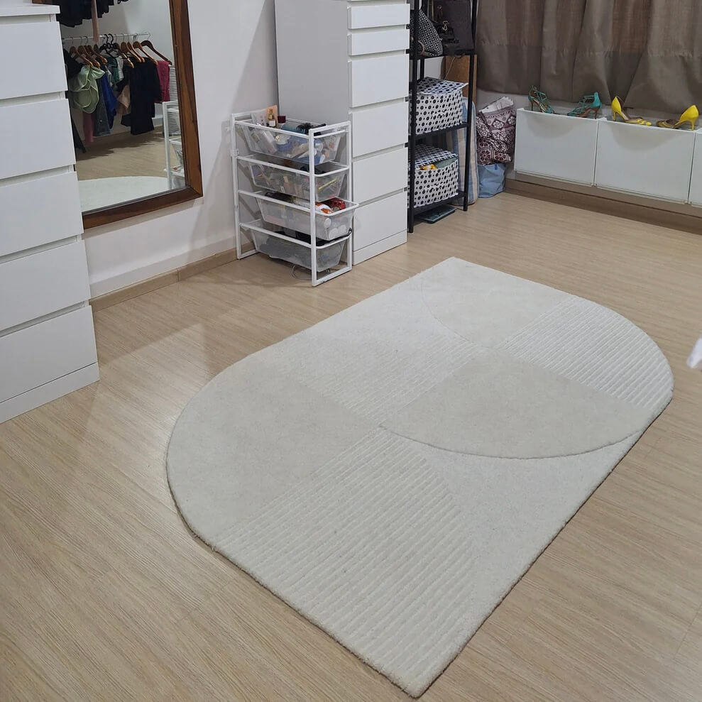 White shaped tufted wool rug on wooden floor