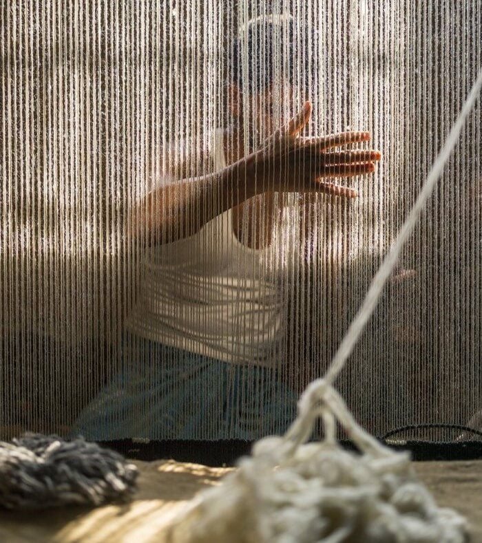 man working with yarn and a loom
