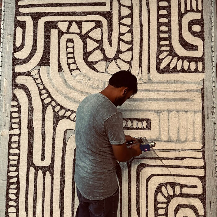 man making a patterned tufted wool rug