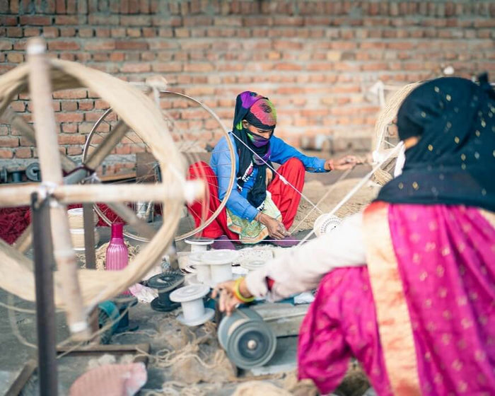 women spinning wool rug thread